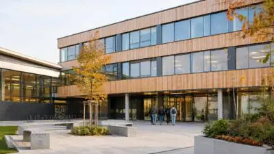 KI-Symbolbild: Ein modernes Schulgebäude mit Holzfassade und großen Fenstern.