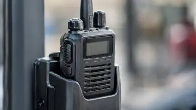 KI-Symbolbild: Ein schwarzes Funkgerät mit Antenne steckt in einer Halterung.