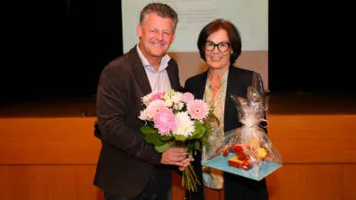 Ein Mann hält einen Blumenstrauß, während eine Frau einen Geschenkkorb trägt.
