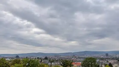 KI-Symbolbild: Eine Stadt liegt unter einem grauen, wolkenverhangenen Himmel.