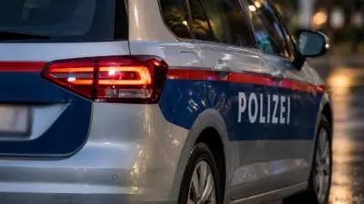 KI-generiertes Bild: Ein silber-blaues Polizeiauto mit rotem Streifen auf einer beleuchteten Straße.