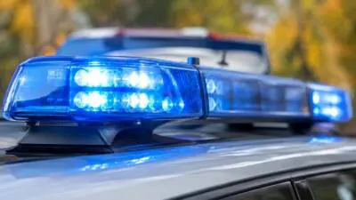 KI-generiertes Bild: Ein blau leuchtender Warnbalken auf dem Dach eines hellen Autos.