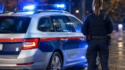 KI-generiertes Bild: Eine uniformierte Person steht neben einem blau-weißen Auto mit Blaulicht.