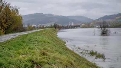 KI-Symbolbild: Ein begrünter Erdwall verläuft neben einer überfluteten Fläche.