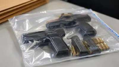KI-Symbolbild: Dunkle Faustfeuerwaffen, Magazine und Patronen liegen in einem durchsichtigen Beutel.