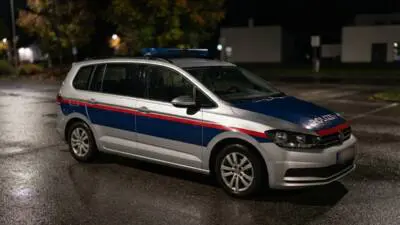 KI-generiertes Bild: Ein silber-blauer Polizeikombi steht nachts auf einer nassen Straße.