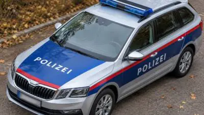 KI-generiertes Bild: Ein silberner Polizeikombi mit blau-roter Lackierung und Blaulicht steht am Straßenrand.