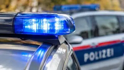 KI-generiertes Bild: Ein leuchtendes blaues Dachlicht auf einem silbernen Auto, dahinter ein weiteres Fahrzeug.