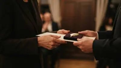 KI-generiertes Bild: Zwei Personen überreichen sich eine Urkunde mit einer goldenen Feder in einer Schatulle.