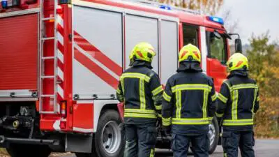 KI-generiertes Bild: Personen in Schutzkleidung stehen neben einem roten Einsatzfahrzeug.