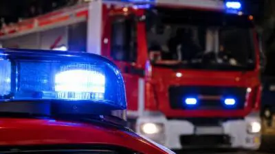 KI-generiertes Bild: Rote Einsatzfahrzeuge mit blauem Blinklicht bei Nacht.