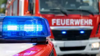 KI-generiertes Bild: Ein blaues Blaulicht auf einem Einsatzfahrzeug vor einem roten Feuerwehrfahrzeug.