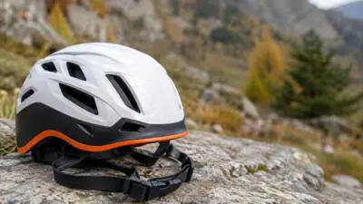 KI-generiertes Bild: Ein weißer Schutzhelm liegt auf einem Felsen vor felsiger Berglandschaft.