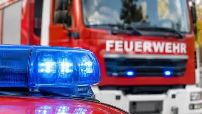 KI-Symbolbild: Ein blaues Blaulicht vor einem roten Feuerwehrfahrzeug.