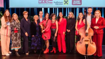 Eine Gruppe posiert beim FrauenWirtschaftsForum auf der Bühne vor einem Banner der Veranstalter.