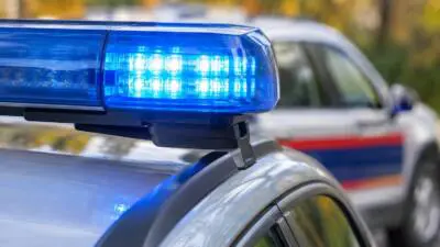KI-generiertes Bild: Blaues Blinklicht auf einem silbernen Auto vor einem weiteren Fahrzeug