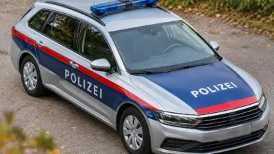 KI-generiertes Bild: Ein silbernes Polizeiauto mit blau-roter Kennzeichnung steht auf einem befestigten Weg.