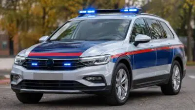 KI-generiertes Bild: Silberner Kombi mit blauen und roten Streifen und blauem Warnlicht.