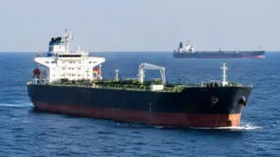 KI-Symbolbild: Ein Tanker auf blauem Meer, ein Frachtschiff am Horizont.