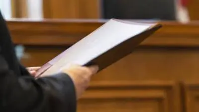 KI-Symbolbild: Eine Person hält ein Dokument vor einer Holzvertäfelung.