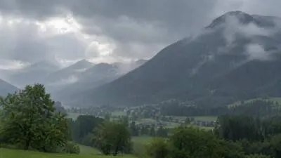 KI-generiertes Bild: Bewaldete Berge um ein grünes Tal unter dunklen Regenwolken