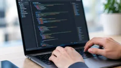 KI-generiertes Bild: Hände tippen an einem Laptop mit Programmcode auf dem Bildschirm.