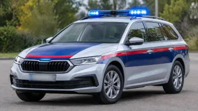 KI-Symbolbild: Ein silberner Kombi mit blauem Blaulicht und rot-blauer Kennzeichnung steht auf einer Straße.
