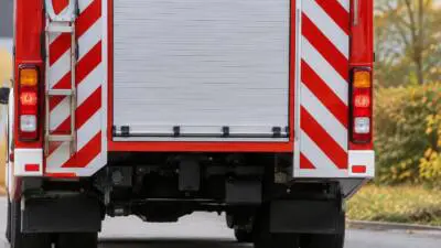 KI-Symbolbild: Heckansicht eines roten Einsatzfahrzeugs mit rot-weißen Warnstreifen.