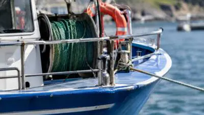 KI-Symbolbild: Ein blau-weißes Fischerboot mit Netz und Rettungsring auf dem Wasser.