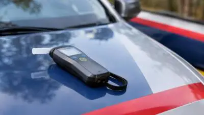 KI-Symbolbild: Ein Alkoholmessgerät liegt auf der Motorhaube eines Autos.