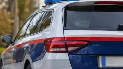 KI-Symbolbild: Nahaufnahme eines weiß-blauen Autos mit rotem Streifen und blauem Dachlicht.