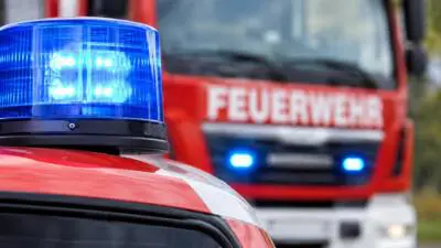 KI-generiertes Bild: Ein blaues Blaulicht auf einem roten Einsatzfahrzeug vor einem Feuerwehrfahrzeug.