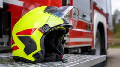 KI-generiertes Bild: Ein gelber Schutzhelm liegt vor einem roten Fahrzeug.