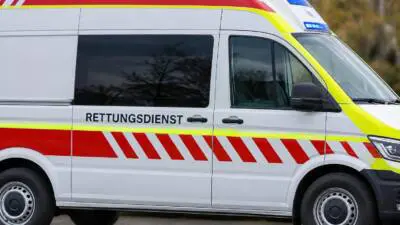 KI-generiertes Bild: Ein weißer Rettungswagen mit roten und gelben Streifen steht im Freien.