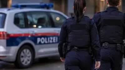 KI-generiertes Bild: Uniformierte Polizeikräfte stehen vor einem weiß-blauen Polizeifahrzeug.