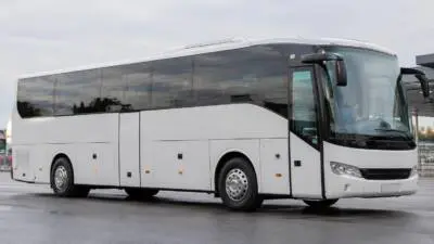KI-generiertes Bild: Ein weißer Reisebus mit dunklen Fenstern auf befestigtem Gelände.