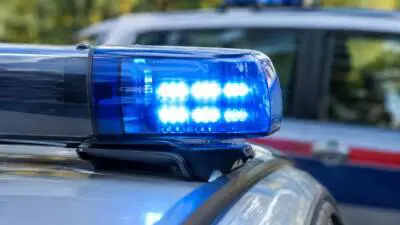Blaues Blinklicht auf dem Dach eines weißen Fahrzeugs vor unscharfem Hintergrund