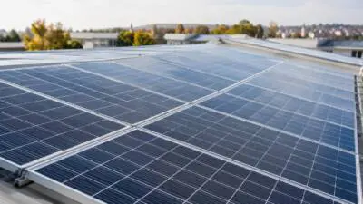 KI-generiertes Bild: Blaue Solarmodule bedecken das Dach eines Gebäudes.