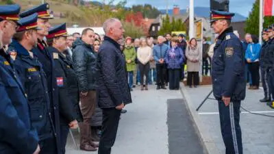 Ein Mann steht einem uniformierten Polizisten gegenüber, während Polizisten und Gäste im Freien zusehen.