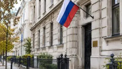 KI-Symbolbild: Eine russische Flagge hängt an der Fassade eines repräsentativen Steingebäudes.