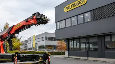 KI-generiertes Bild: Ein roter Fahrzeugkran vor modernen Bürogebäuden.