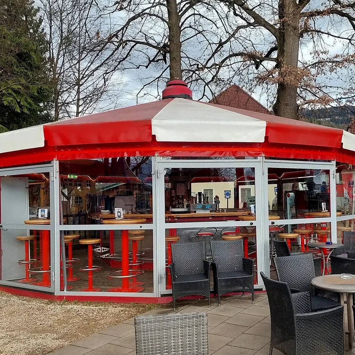 Ein Café mit rot-weißem Dach und verglaster Terrasse