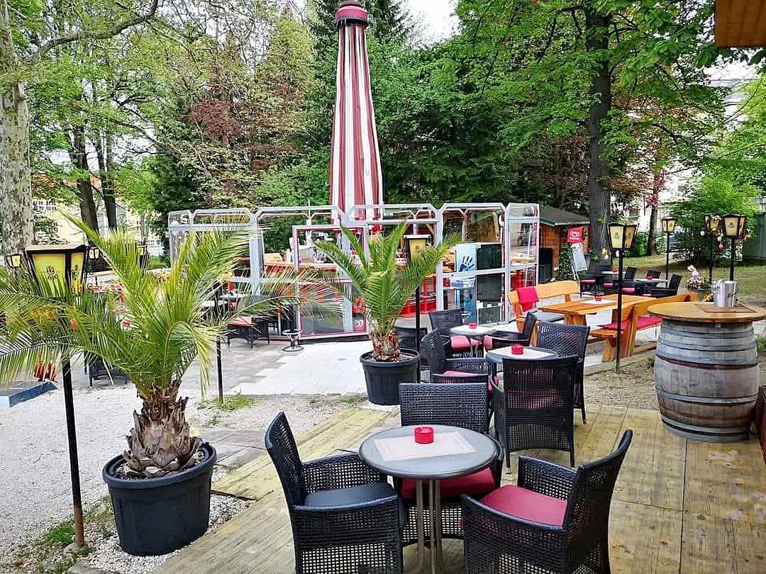 Außenterrasse eines Cafés mit Tischen, Stühlen und Topfpflanzen