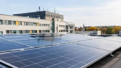 KI-Symbolbild: Dunkelblaue Solarmodule auf dem Flachdach eines modernen Gebäudes.