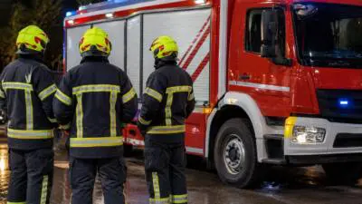 KI-generiertes Bild: Personen in Schutzkleidung stehen neben einem roten Einsatzfahrzeug.