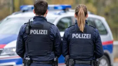KI-generiertes Bild: Polizeikräfte in dunkler Uniform vor einem Polizeiauto.