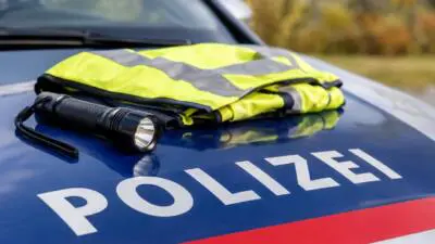 KI-generiertes Bild: Eine Warnweste und eine Taschenlampe liegen auf einem Polizeiauto.
