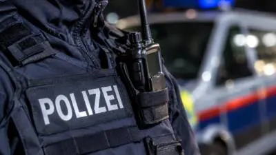 KI-generiertes Bild: Eine Polizeikraft mit Funkgerät vor einem unscharfen Fahrzeug.