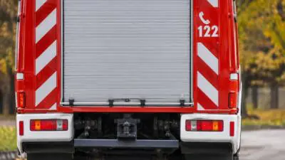 KI-Symbolbild: Heck eines roten Feuerwehrfahrzeugs mit silbernem Rollladen.