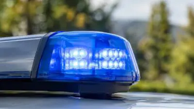 KI-generiertes Bild: Ein blaues Signallicht auf dem Dach eines hellen Fahrzeugs.